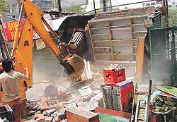 An administration bulldozer demolishes a shop near the Red Cross Bhavan on Mall Road