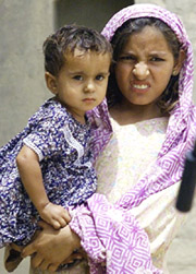 Two-year-old Ifra is carried by her cousin