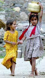 Two village girls carry home water