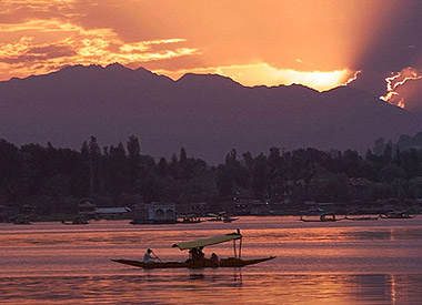 A man rows his boat across Dal Lake