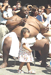 Two-year-old Megan Kawaguchi walks past 720-pound American Sumo wrestler