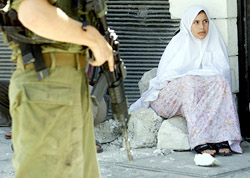 An Israeli soldier guards a Palestinian woman