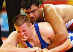Canada's Eric Ronald Kirschner grimaces as he is held down by India's Palwinder Singh Cheema