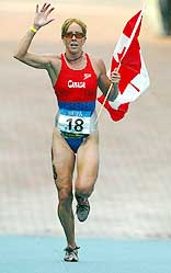 Canada's Carol Montgomery celebrates as she runs to the finish line to win the women's triathlon
