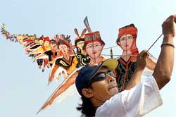 An Indonesian man flies a kite featuring national Indonesian costumes