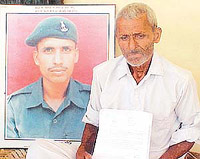 Mr Ishan Ram, father of Kargil martyr Pawan Kumar Saini, with his son�s photograph. 