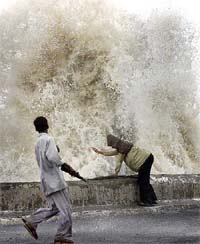 An Indian boy looks at large waves crashing into the shore