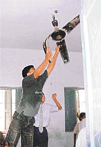 Agitating students try to damage a fan in a classroom