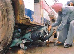 The driver of the bus which ran over a scooter near Dandi Swami Chowk in Ludhiana on Tuesday tries to take it out