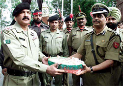 Commander of Pakistani Border Guards Col. Sher Zaman (L), receives sweets from his Indian counterpart 