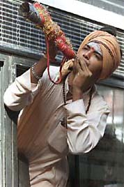A devotee plays a traditional trumpet
