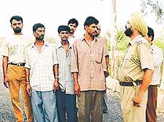 A police official questions migrant labourers in connection with murder of a labourer in Ludhiana on Saturday.