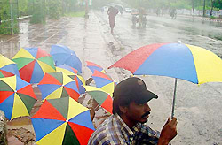 A vendor sells umbrellas on a street during a rainy day