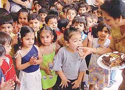 Ms Amrita Garewal, Principal, Hollyhock Nursery School, distributes cake among children 