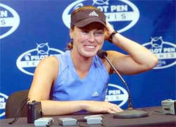 Martina Hingis smiles and adjusts her visor