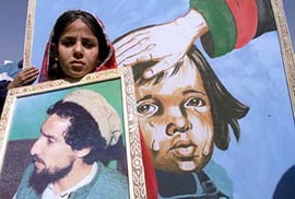 An Afghan girl holds a portrait of the assassinated leader of the anti-Taliban alliance Ahmad Shah Masood
