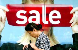 A Chinese woman walks past a poster promoting a store on sale in Beijing