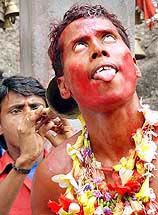 A pilgrim covered in red powder performs the traditional Deodhani dance