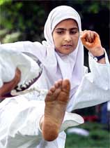 A Kashmiri Muslim girl wearing the traditional head scarf practices Taekwondo