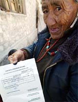 An elderly Ladakhi woman holds papers to receive her voter identity card