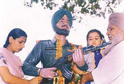 Sister of martyr Paramjit Singh ties a rakhi to his statue at Gill village on Thursday. His father and daughter are also in the picture.