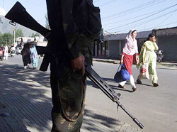 Two women walk past a paramilitary jawan