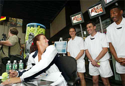 Jennifer Capriati laughs as three men with portable televisions playing a commercial featuring herself stand behind her