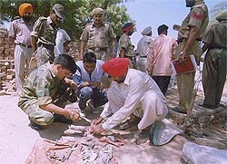 Senior Army and police officials check the remains of the crude bomb which killed Mal Ram, a junk dealer, at Nathana (Bathinda) on Sunday