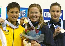 Natalie Coughlin of the USA shows off her gold medal with Australian silver medallist Dyana Calub and compatriot bronze medallist Haley Cope  after winning the women's 100-metre backstroke final