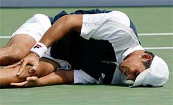 Mark Philippoussis of Australia clutches his knee after injuring it going up for an overhead shot against Sjeng Schalken 