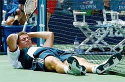 Marat Safin of Russia lies on t he court after tumbling into the net during his US Open match