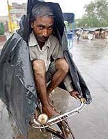 A man riding a rickshaw covers himself during rain
