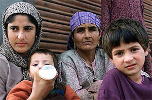 A Kashmiri mother feeds her baby while watching an election rally