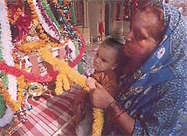 A devotee along with her grandchild at a temple to participate in Janamashtmi celebrations