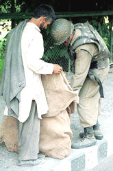 A BSF jawan frisks a coolie