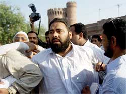 Plain-clothes policemen detain a worker of the Mutahidda Majlis-e-Amal 