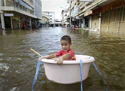 A boy floats in a plastic tub down the flooded main street of the central Thai town of Taphan Hin