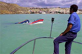 An Italian coastguard officer examines the broken remains of a ship