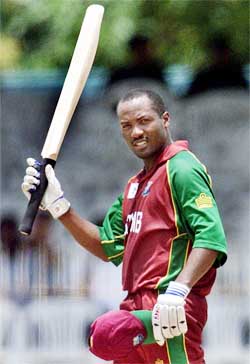 Brian Lara of the West Indies raises his bat to acknowledge completing his century