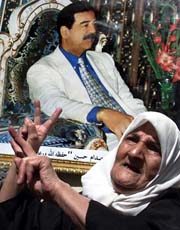An Iraqi woman dances in front a picture of President Saddam Hussein