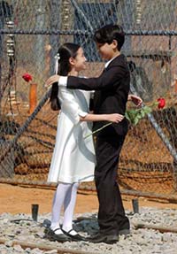 Holding a flower, a South Korean boy and a South Korean girl, play the role of a North Korean girl