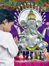 A girl prays in front of the idol of Lord Ganesh