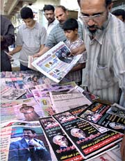 Iraqis buy newspapers in a street in Baghdad