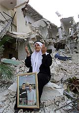 A Palestinian woman prays with a picture of her sons