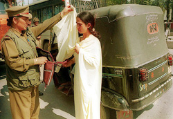 A woman police officer checks a Kashmiri girl 