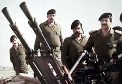 Saddam Hussein stands with his guards behind him at an artillery piece