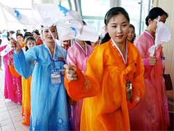 Dressed in colorful traditional robes, North Korean women wave "unification" flags