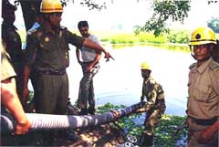 Fire brigade personnel pumping out water from the pond
