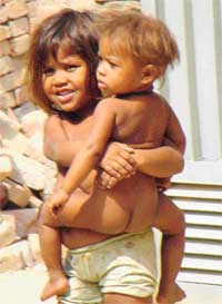 A young girl carrying her brother while her mother works as a labourer is a common site 