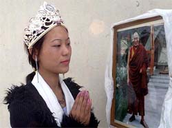 Dolma Tsering of India, winner of the first Miss Tibet pageant, prays in front of a photograph of the Tibetan spiritual leader